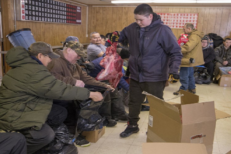 Deacon Phillip Yupanik from the village of Emmonak accepts a gift of moose meat from a youth at a potlatch.