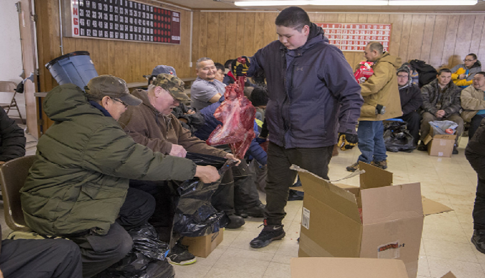 Deacon Phillip Yupanik from the village of Emmonak accepts a gift of moose meat from a youth at a potlatch.
